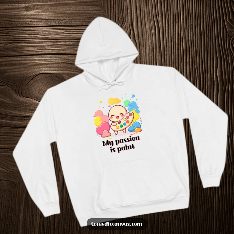 Funny hoodie depicting a cheerful palette character immersed in playing with vibrant blobs of paint, showcasing artistic joy.